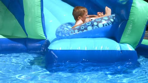 Boy Playing On Water Slide Slow Motion
