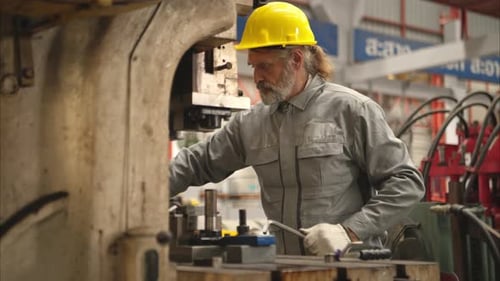 Senior experienced technician checking and maintenance a large machine in metal sheet factory