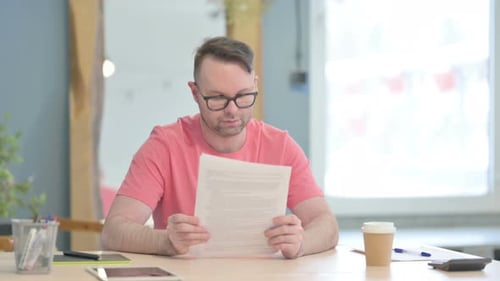 Man Reading Documents at Office Desk