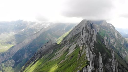Aerial flyover over and away from the cliffs of Schafler ridge in Appenzell, Switzerland with cliffs
