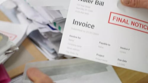 Close up of a man opening debt letters. The letter shows a water bill final notice