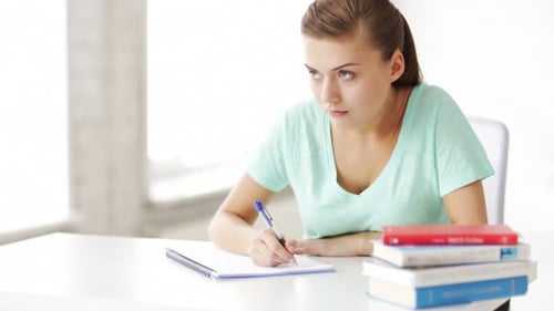 Girl Studies at Desk, Writes in Notebook