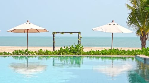 Luxury Tropical Poolside, Beach Arch, Parasols and Reflection on Pool Water on Sunny Day, Full Frame