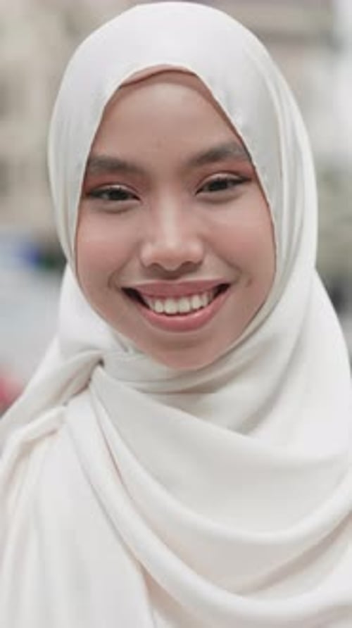 Portrait of the Beautiful Smiling Face of the Muslim Girl Standing in the City in Traditional Pink