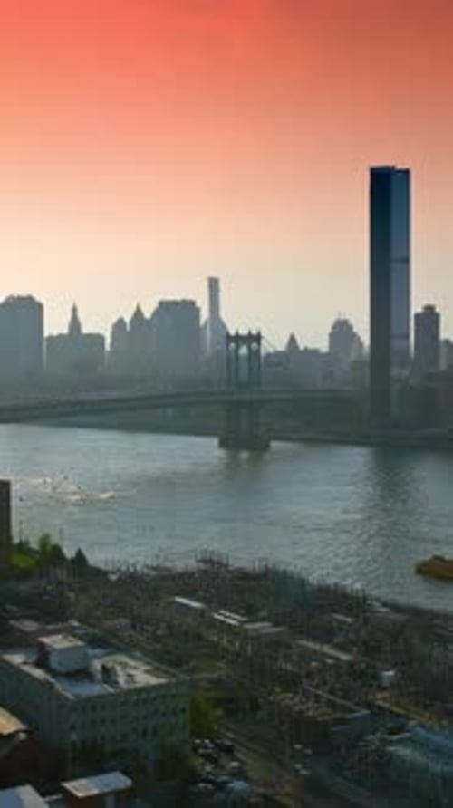 Beautiful sun in the pink sky shining over New York. City docks, Manhattan Bridge over East River