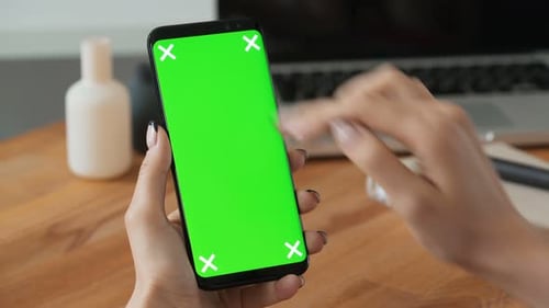 Person Using Cell Phone With Green Screen Display In Hand And Woman Make A Gesture. Closeup Conce...