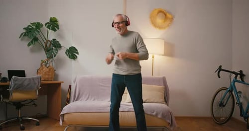 Senior Man Dancing in Living Room with Headphones