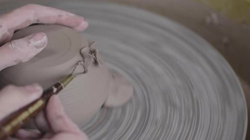 Person sculpting clay into a mug on a potters wheel.