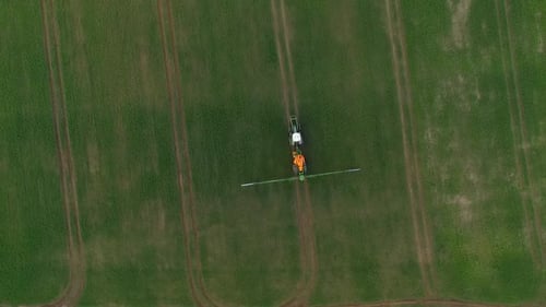 Pesticide and fertilizer spraying on the field aerial view with tractor