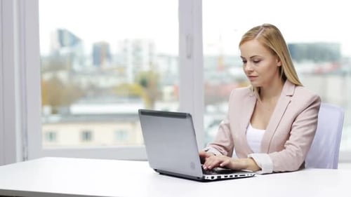 Woman typing on laptop in bright office