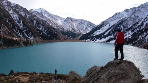 The Guy is Standing on a Rock Overlooking the Lake