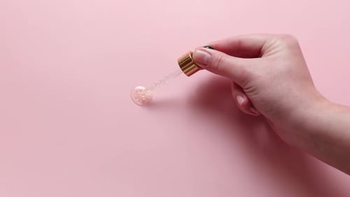 Close Up of Dropper with Cosmetic Serum Woman Holding Glass Pipette with Skincare Liquid on Beige