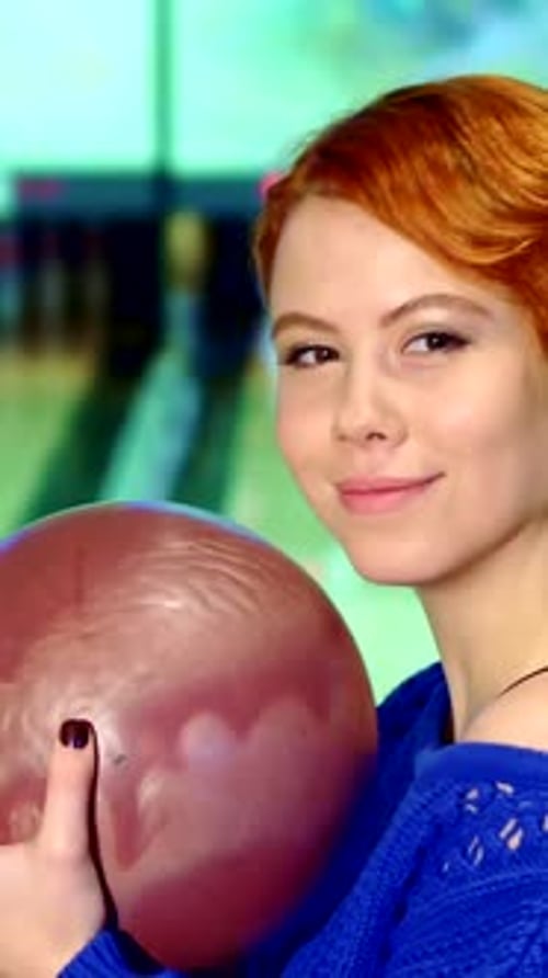 Cheerful Girl Holding a Bowling Ball Ready to Strike