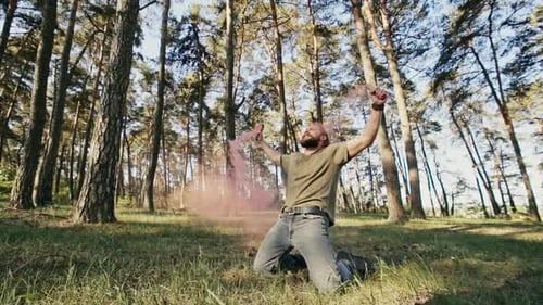 Man with Smoke Signals Kneeling in Sunny Forest