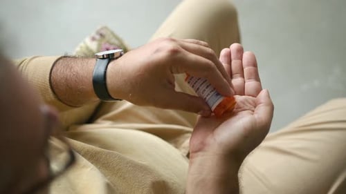 Man Pours Pills into Hand from Prescription Bottle