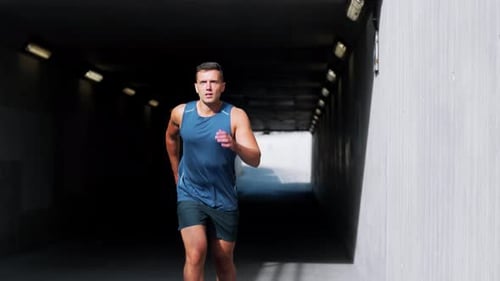 Determined young man running out of tunnel for outdoor city workout and training