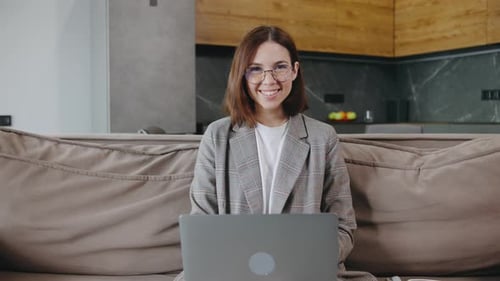 Woman Smiling and Using Laptop on Couch at Home