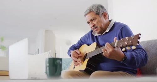 Senior Adult plays Acoustic Guitar at Home