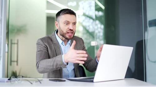 Angry Man Arguing at a Laptop in Office