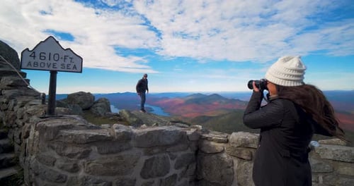 Couple hiking up rocky mountain steps in summer adventure with lens flare