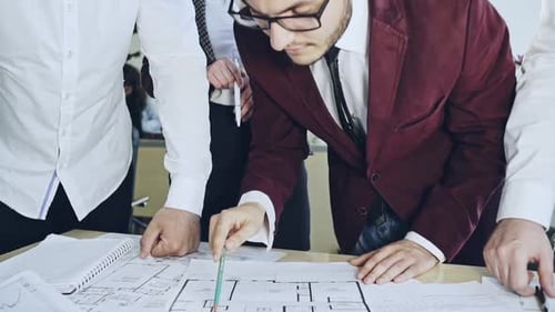 Team Analyzes Architectural Plans in Modern Office