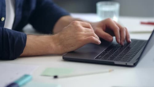 Man hands typing on laptop computer keyboard at remote workplace in slow motion