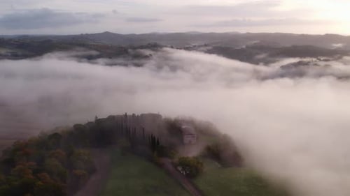 Tuscany hill landscape covered in thick morning mist, aerial