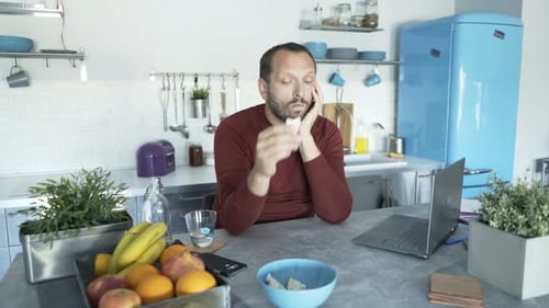 Young, Bored Man Sitting in Kitchen 30s
