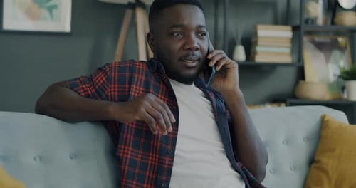 Young Man Talking on Smartphone While Sitting on Sofa