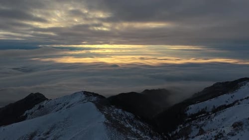 Panorama-Luftdrohnenaufnahme des goldenen Sonnenaufgangs über den Wolken, Winterlandschaft in den Bergen. Trans