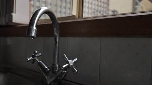 Water Dripping from Shiny Silver Bathroom Faucet