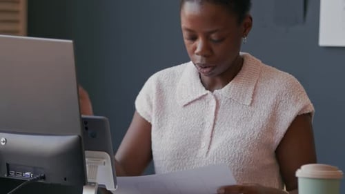 Young Black Woman Analyzing UI Design for Mobile App on Paper Working at Office