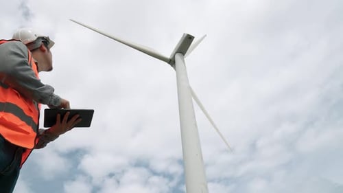 Progressive Engineer Working with the Wind Turbine with the Sky As Background