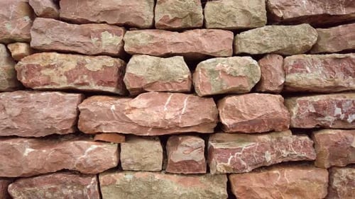The Camera Moves Smoothly Along a Wall Made of Pink Stones of Natural Origin Closeup