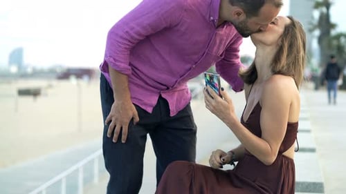 Happy couple meeting near the beach in coastal city checking phone together