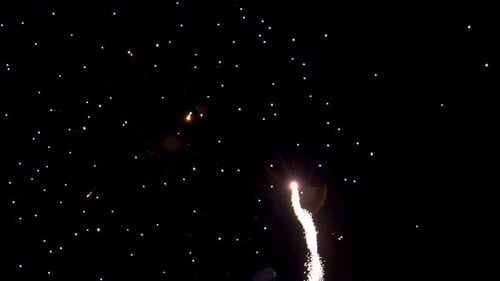 Sparkles and shimmering light of fireworks exploding in the dark black night sky. Colorful explosion