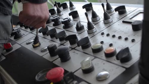 Hand of operator using joystick on control panel of road paving machine