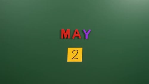 Hand sticking a sticker 2 May calendar day on school board. 2 date of May. Second day May. 2nd
