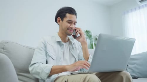 Young Adult Works on Laptop and Talks on Phone