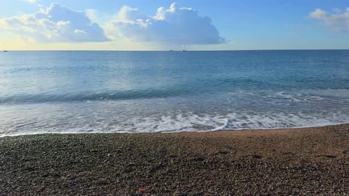 Sandstrand und kleine Steine in Zeitlupe mit kleinen Wellen