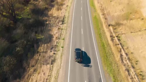 A Car with Bicycles on a Trailer is Driving Along a Road Shooting From a Drone