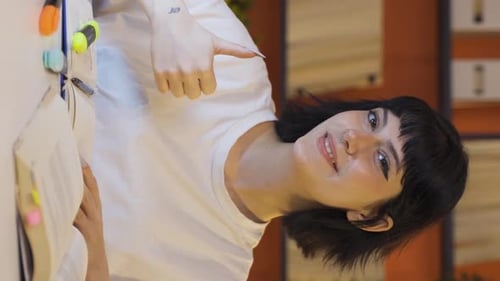 Smiling Young Adult Studying at Table Gives Thumbs Up