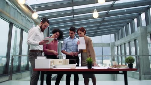 Young architects discussing house model in modern office workplace