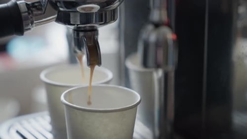 Espresso machine pouring coffee into cups close up