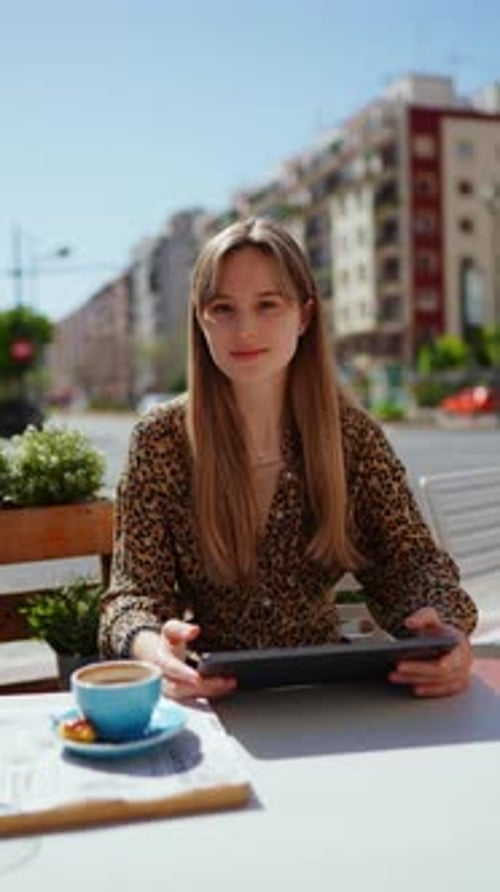 Young Woman Relaxing at Street Cafe Terrace Working Remotely on Tablet While Drinking Coffee