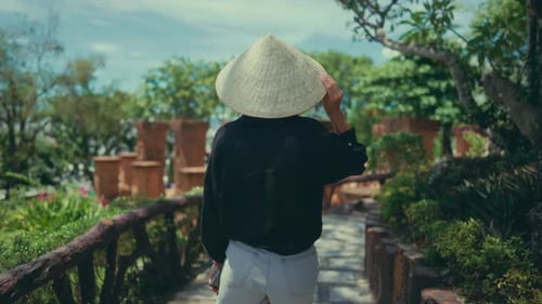 Sightseeing and Travel in Asia Women in Conical Hat Walking in Park Back View Summer Vacation and