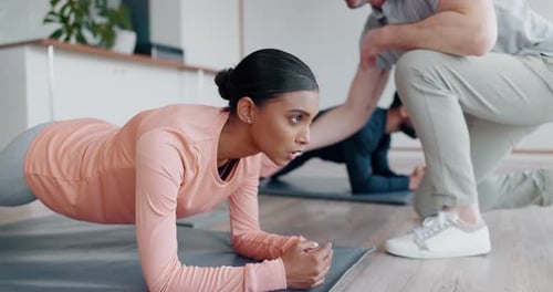 Woman Doing Plank Exercise with Trainer Indoors