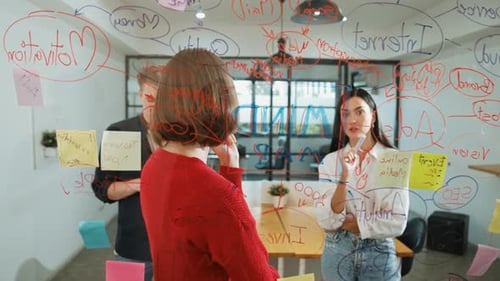 Creative Team Brainstorming Ideas on Glass Wall in Office