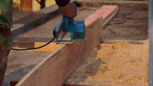 Person Planing Wood Plank with Electric Planer