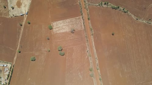 High angle tilt up over dry meadows, revealing large farm buildings